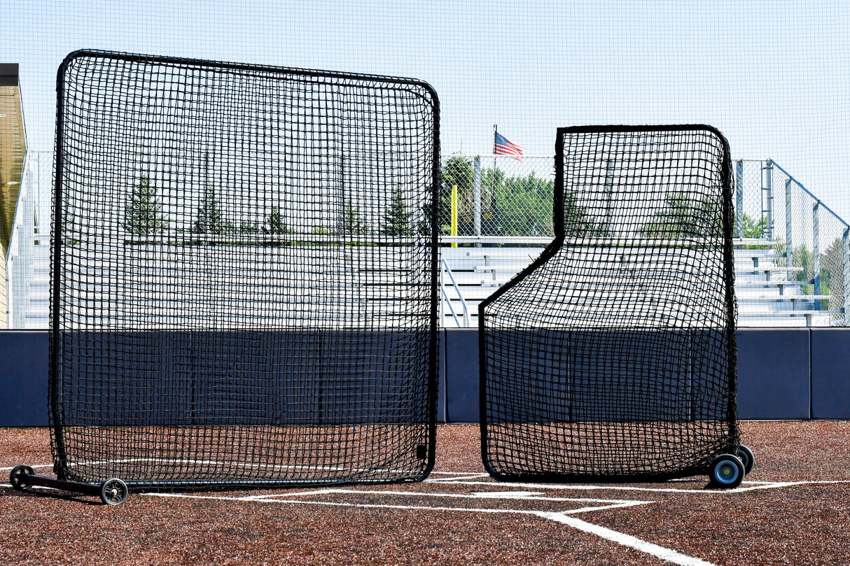 Two black protective screens on a turf baseball field with a clear sky.