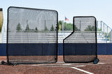 Two black protective screens on a turf baseball field with a clear sky.